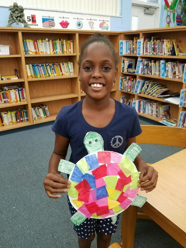Student presenting a homemade mosaic turtle
